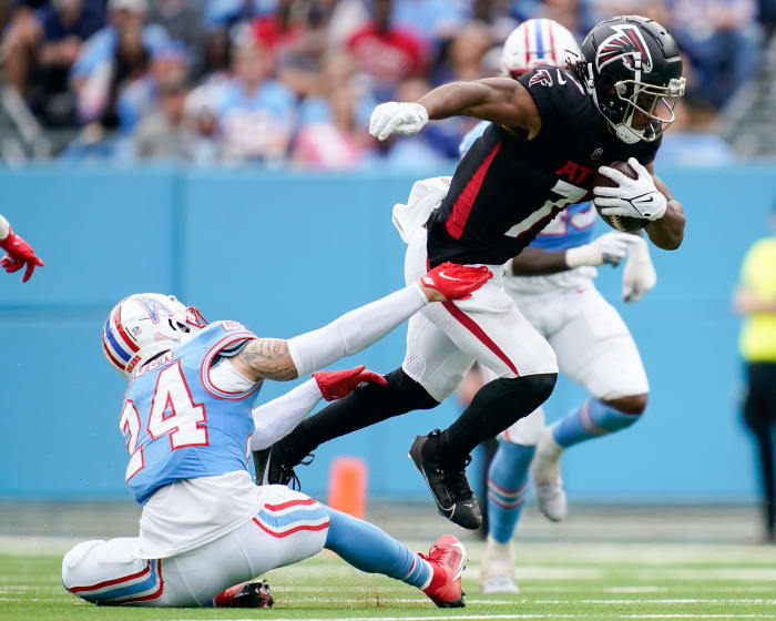 Bijan Robinson leaps while holding the ball as a Titans defender tries to grab his legs